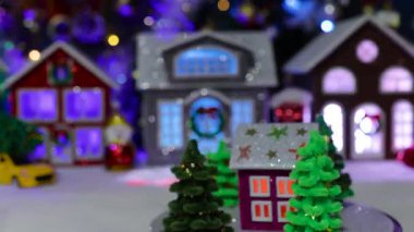 Noel ağaçlarıyla çevrili koyu pembe bir evin yakın çekimi büyük bir Noel kasabasının merkezinde dönüyor.