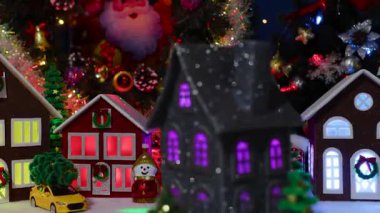 Noel ağaçlarıyla çevrili, büyük bir Noel kasabasının merkezinde dönen koyu gri bir evin yakın çekimi.