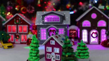 Büyük bir Noel köyünün ortasında dönen Noel ağaçlarıyla çevrili koyu pembe bir evin yakın çekimi.