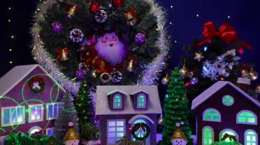 Noel köyünde büyük bir Noel ağacı ve Noel çelengi karşısında renkli arabalar ve kardan adamlar evlerin önünde duruyor.