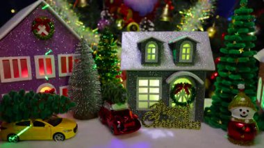 Büyük bir Noel ağacının ve Noel çelenginin önünde, evlerin, arabaların ve mektupların önünde.