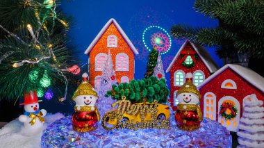 Noel kasabasında, evlerin önünde, sarı arabalı kardan adamlar ve bir stantta mektuplar var.