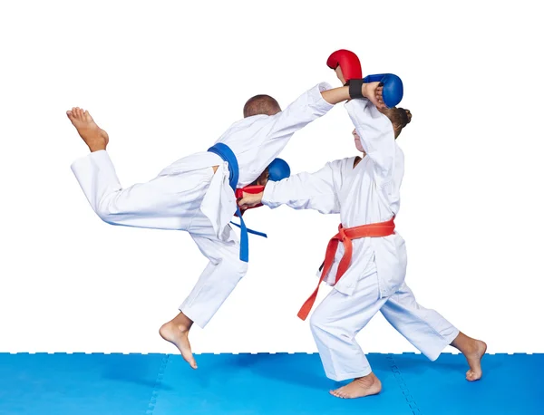 Flicka och en pojke slår karate slag på mattan isolerade — Stockfoto