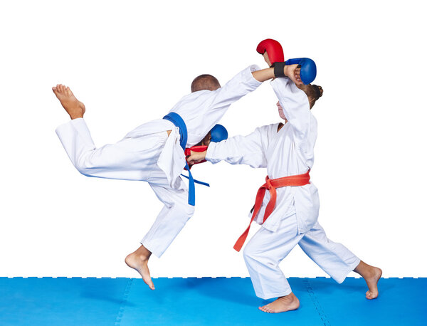 Girl and boy are beating karate punches on the mat isolated
