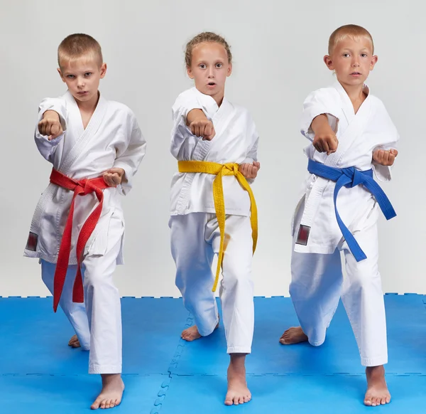 On a light background three athletes beat punch gyaku-tsuki — Stock Photo, Image