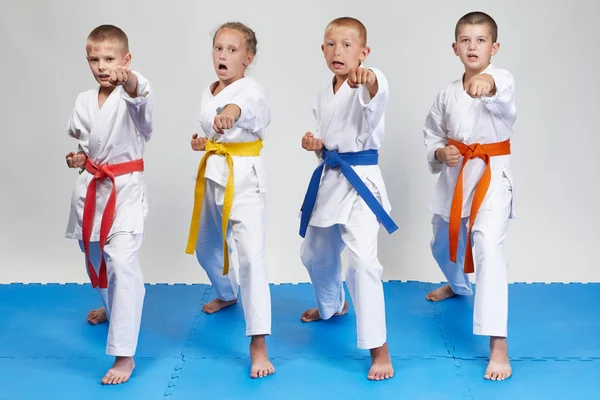 Menina e meninos estão treinando kizami-tsuki hit em karategi — Fotografia de Stock