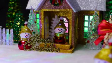 Elinde zil ve Noel ağacı olan bir kardan adam verandasında bir kardan adam ve yanında Noel ağacı olan bir kardan adam olan bir evin arka planına karşı.