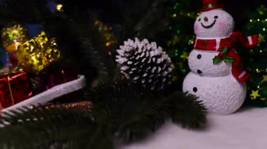 Kızak hediye eden kardan adamlar ve Noel ağacı dalları arasında mektuplar ve ortadaki süslemeli ışıklar yanıp sönen ışıklarla aydınlatılıyor.