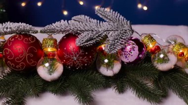 Koyu mavi arka planda Noel ağacı dalları var. Güzel ışıklar ve Noel toplarıyla süslenmiş.