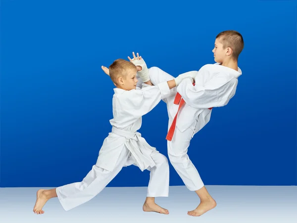 Auf blauem Hintergrund schlagen Sportler Karate-Schläge — Stockfoto