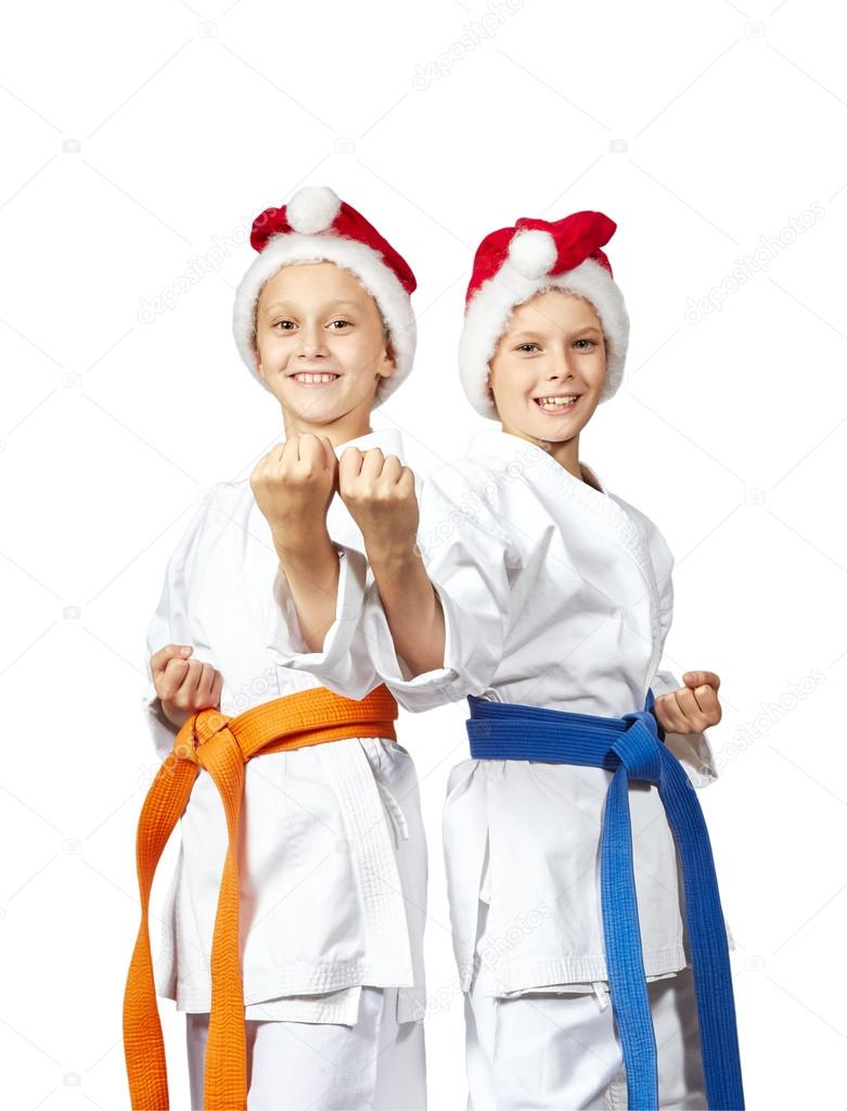 Two athletes in caps of Santa Claus standing in rack of karate