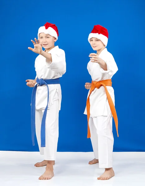 Sportsmens in caps of Santa Claus standing in rack of karate — Stock Photo, Image