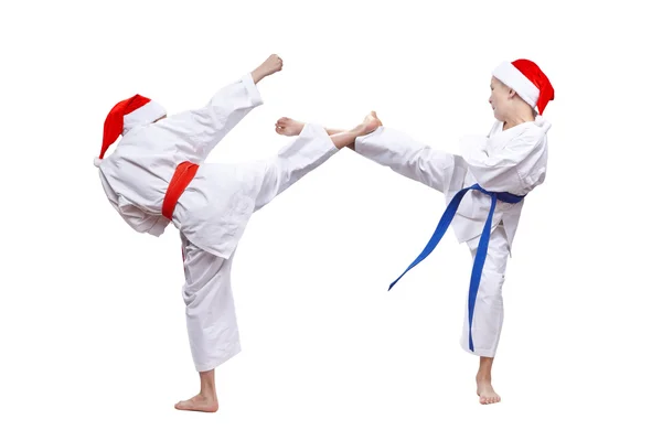 Chłopcy w czapki Santa Claus pokonać kopnięcie nogą — Zdjęcie stockowe