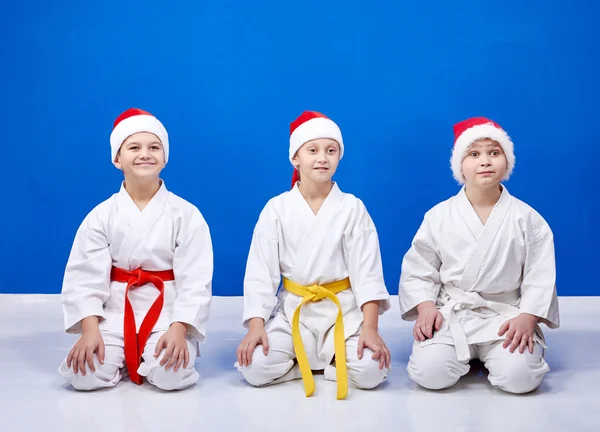 Barn i cap Santa Claus sitter i pose karate — Stockfoto
