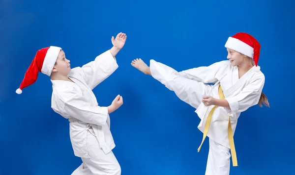 Cheerful children in cap of Santa Claus are training karate techniques — Stock Photo, Image