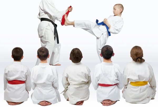 Sporters zitten in pose kijken naar demonstratie punch karate — Stockfoto