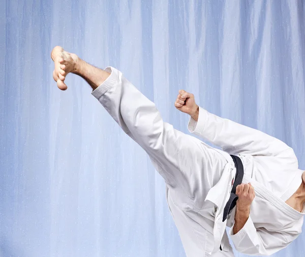 On a light background a man beats a high kick — Stock Photo, Image