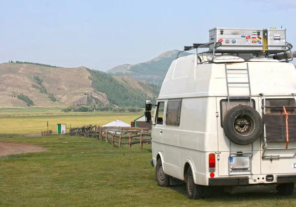 Moğolistan / 28 Temmuz 2019: Yeşil tepelere park edilmiş eski beyaz klasik minibüs. Seyahat, kamp, karavan topluluğu konsepti.