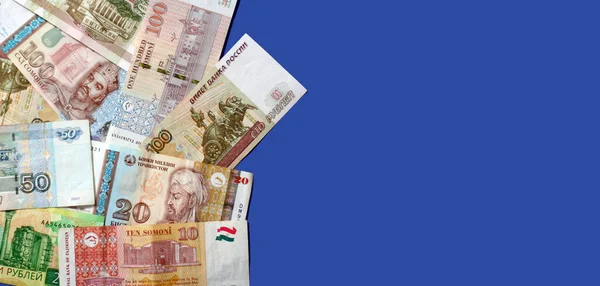 照片上有塔吉克斯坦的索莫尼钞票和蓝色背景的俄罗斯卢布钞票 横幅尺寸 复制空间 专注于金钱 — 图库照片