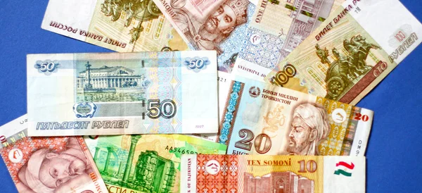 照片来自塔吉克斯坦的索莫尼钞票和蓝色背景的俄罗斯卢布钞票 — 图库照片