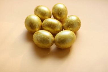 Açık sarı arka planda altın yumurtaları olan Paskalya arkaplanı. Poster, reklam, poster, kartpostal için şablon. Mutlu Paskalya arkaplanı üst görünümü, kopyalama alanı.