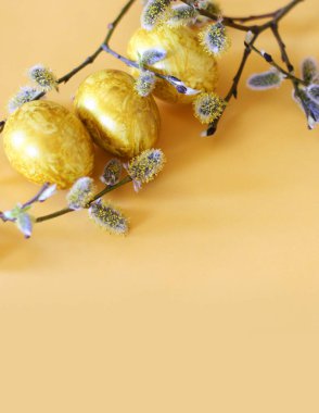 Altın yumurtalı ve sarı arka planda söğütlü Paskalya arkaplanı. Poster, reklam, poster, kartpostal için şablon. Mutlu Paskalya arkaplanı üst görünümü, kopyalama alanı.