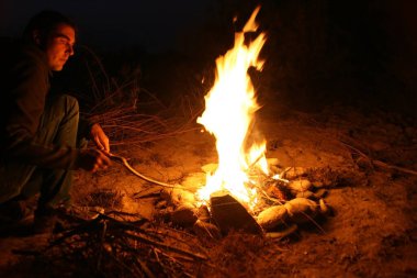 Kamp ateşi. Geceleri kamp ateşi etrafında turist silueti. Şenlik ateşi, karanlık gece, tepeden manzara. Alev yaraları merceğe dönüşür.
