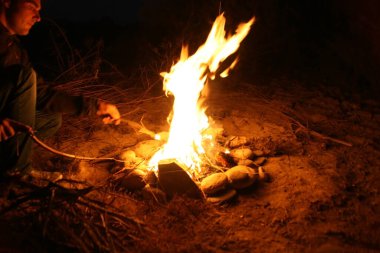 Kamp ateşi. Geceleri kamp ateşi etrafında turist silueti. Şenlik ateşi, karanlık gece, tepeden manzara. Alev yaraları merceğe dönüşür.