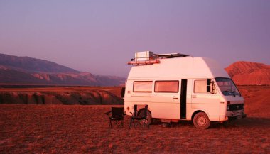 Kırgızistan - 10.09.2019: Gün batımında dağlarda araba. Kırgızistan 'daki dağ manzarası. Dağ vadisi manzarasında kayalar, çimenler ve taşlar. Dağ manzarası.