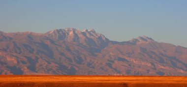 Kırgızistan dağlarında gün batımı. Keskin siyah dağların üzerinde parlak turuncu bir gün batımı