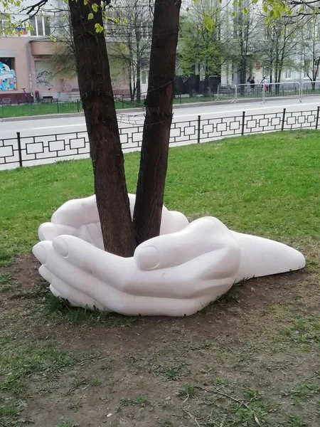 Yekaterinburg, Russia - May 5, 2021: Sculpture on the street. White hands are holding a tree sculpture. The symbol of conservation and protection of nature. eco consept,  take care of nature