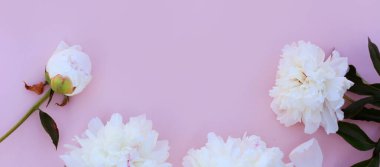 Sahte davetiye, boş kağıt tebrik kartı, pembe masa ve şakayıklar. Çiçek arkaplanı. Düz yatış, üst görünüm.