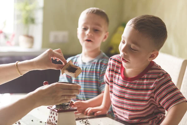 Twin brothers helping her mother to grind coffee — Stock Photo, Image