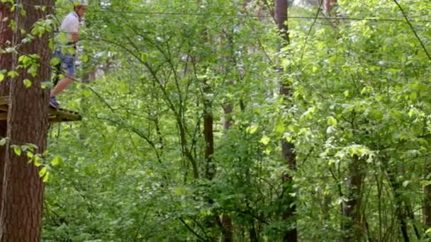 Mladý muž sestupuje z nástupiště u stromu na laně — Stock video