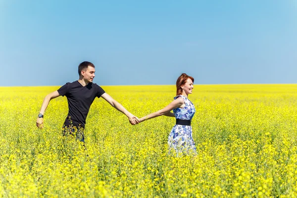 幸福的夫妇在黄色的草地中运行的图像 — 图库照片