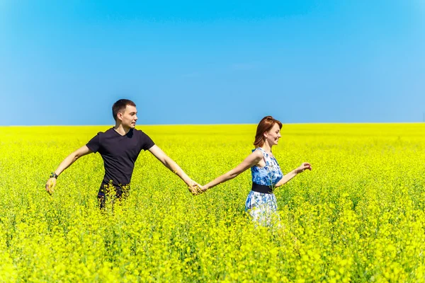 노란 풀밭에서 실행 하는 행복 한 커플의 이미지 — 스톡 사진