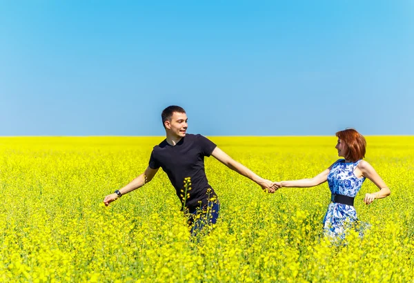 Изображение счастливой пары, бегущей по желтому лугу — стоковое фото