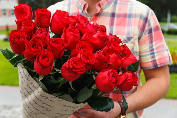 Un hombre llevando un enorme ramo de rosas rojas — Foto de Stock