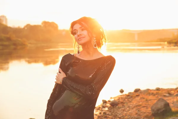 Schöne junge modische Frau posiert im Kleid an der Flussküste — Stockfoto