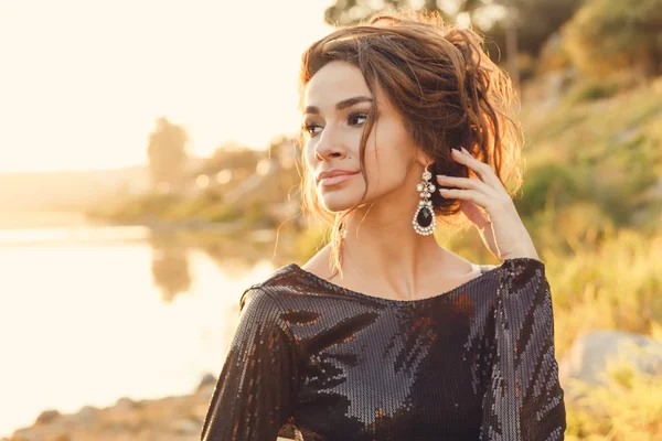 Beautiful young fashionable woman posing in dress at the river coast — Stock Photo, Image