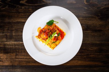 Beyaz tabakta ıspanak ve karamel soslu omlet. Üst görünüm.