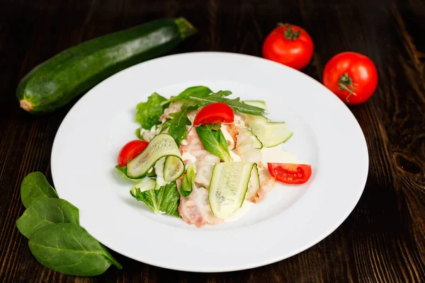 新鮮な野菜サラダ レタス アルグラ キュウリ トマト を木製のテーブルの背景に白いプレートに揚げベーコンで閉じます — ストック写真