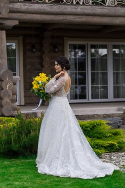 Büyüleyici gelin bir düğün buketi saklıyor ve bahçede poz veriyor.