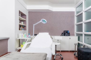 Bir güzellik salonundaki modern kozmetoloji odasının içi aydınlık. Kozmetik uzmanı. Güzellik salonundaki dolapta kozmetik kanepe ve diğer malzemeler var..