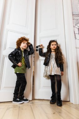 Deri ceketli kız ve erkek bir evin içinde birlikte poz veriyorlar.