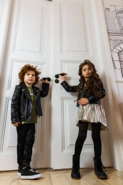 Deri ceketli kız ve erkek bir evin içinde birlikte poz veriyorlar.