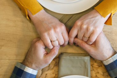 Restoranda romantik bir akşam yemeği yiyen genç bir çift evlilik yüzüğü takıyor.