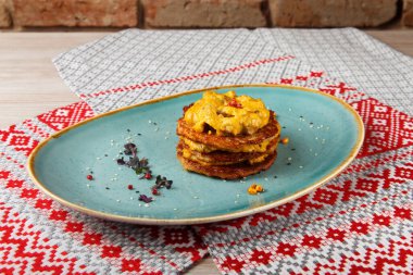 Krema soslu patatesli gözleme. Bir restoranda ulusal süs eşyasıyla peçetede..