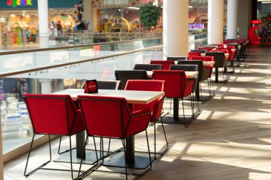 Modern bir alışveriş merkezinin yemek bölümüne ziyaretçiler için yumuşak sandalyeli bir sıra masa. İnsanlar yemek boyunca güzel manzaraya hayran kalırlar..