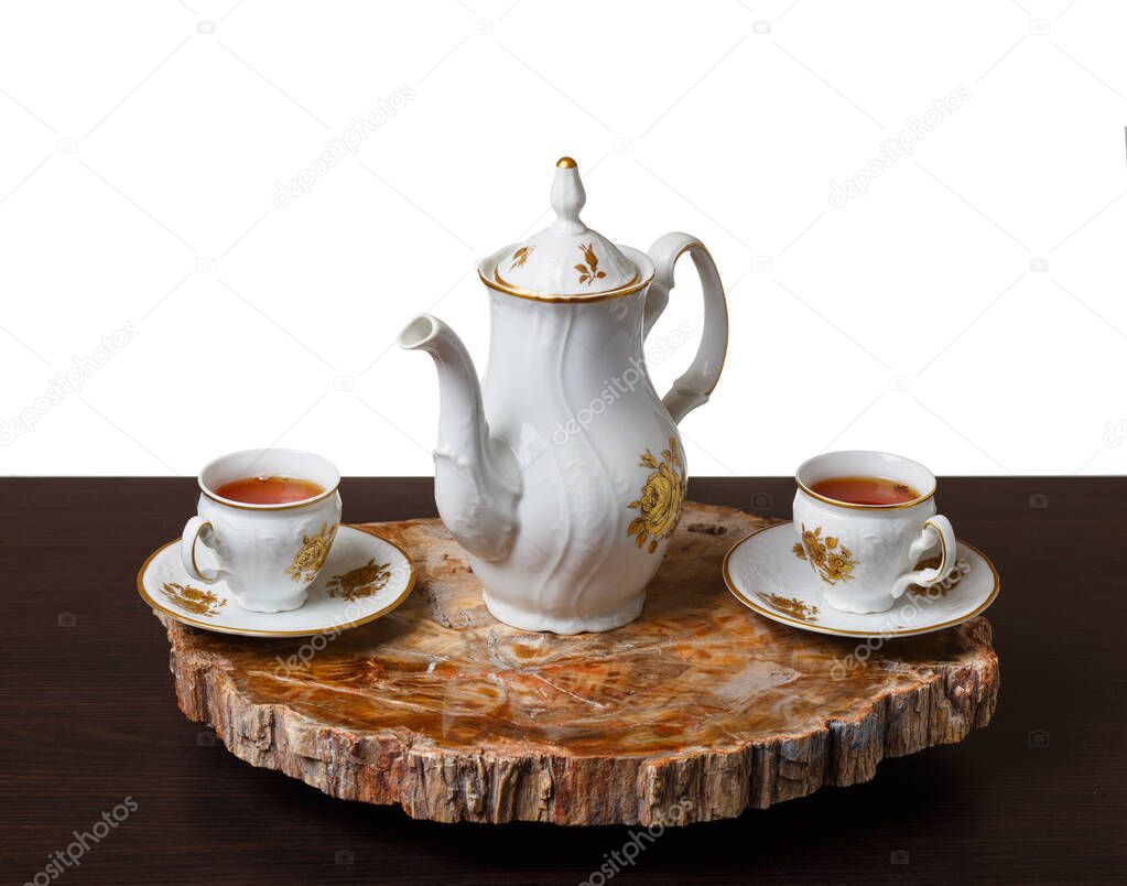 Elegant coffee set on an exclusive tray made from a cut of ancient petrified wood. Isolated on white background.